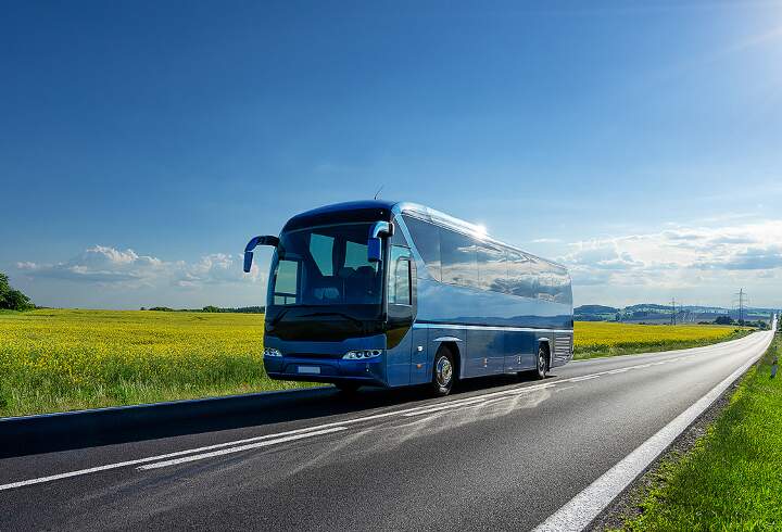 Charter bussi matkalla halki kauniin kesäisen peltomaiseman.