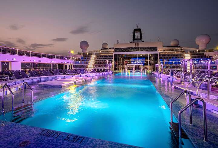 MSC World American upea aurinkokannen uima-altaat iltavalaistuksessa.