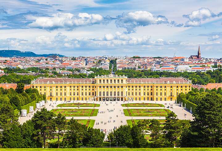 Klassinen näkymä kuuluisaan Schönbrunnin palatsiin ja sen luonnonkauniiseen Parterre-puutarhaan kauniina aurinkoisena kesäpäivänä sinisen taivaan ja pilvien kera Wienissä Itävallassa.
