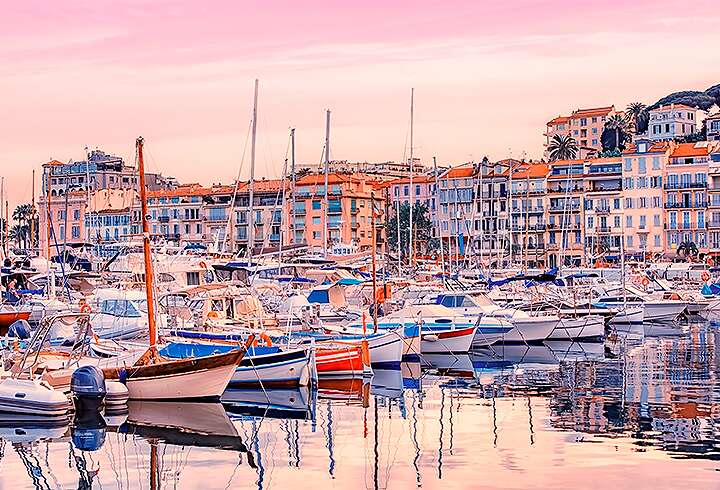 Cannesin rantakaupungin satama-alue vaaleanpunaisella taivaalla. 