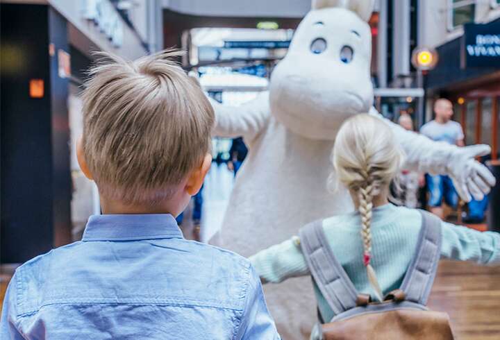 Muumipeikko aikoo halata kahta lasta Silja Serenaden promenadella. 